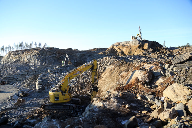 Her pigges det i forgrunnen og bores i bakgrunnen. I midten til venstre bygges deler av den totalt 1000 kvadratmeter store natursteinsmuren på området. (Foto: Runar F. Daler).