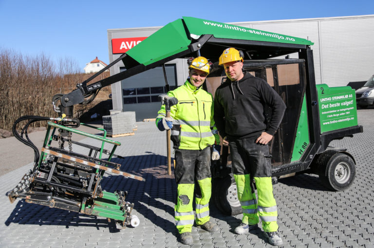 Adrian Mróz (med slegga) og Artur Paul er proffe og erfarne steinleggere – med glimt i øyet. (Foto: Runar F. Daler).