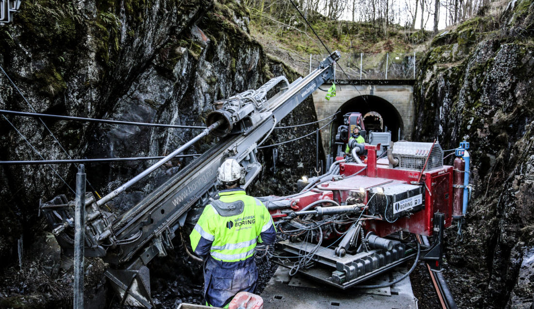 TRANGT: Ikke bare er det trangt til fjellveggen på begge sider, men kjøreledningen befinner seg bare noen få meter over riggen. Men Truls Omland Aasheim styrer med stø hånd mens Bård Magnus Dalen følger nøye med. (Foto: Runar F. Daler).