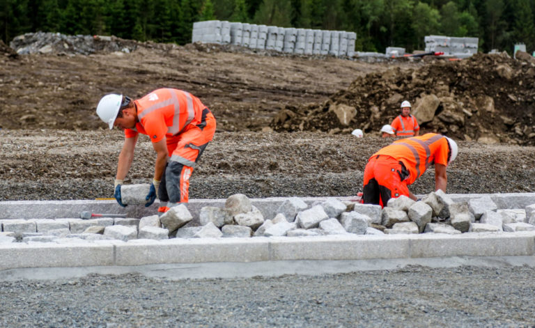 STEINLEGGING: Her legges steiner rundt en av de nye rundkjøringene. Det er Landskapsentreprenørene som utfører jobben. (Foto: Runar F. Daler).