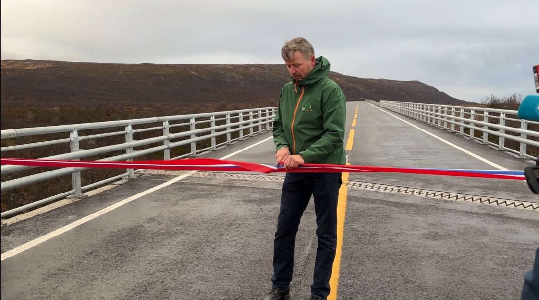 Statssekretær Stein Mathisen klipper snora og åpner den nye veistrekningen på E6 i Finnmark med ny bro over Vuolmmašjohka. (Foto: Ida Lundgren Kristensen/Statens vegvesen)