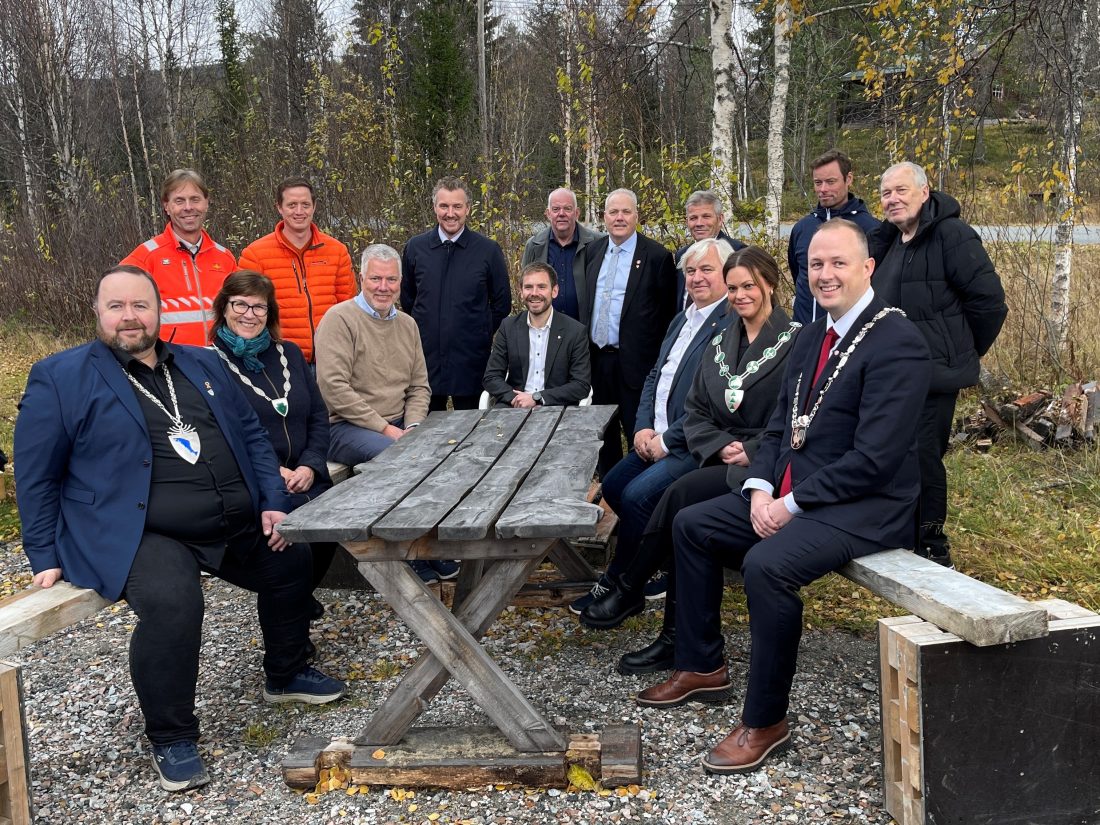 Historisk svung: Med stor entusiasme benket politikere, entreprenører og vegvesenets ledere seg i dag rundt et grovt snekret trebord på Helgeland, for å gjenskape en av landets viktigste vegåpninger 100 år etter. Rundt bordet fremme fra venstre: Raymond Fagerli, ordfører i Grane (Sp), Sølvi Andersen, ordfører i Hattfjelldal (AP), Ove Myrvåg, assisterende vegdirektør Statens vegvesen, Tom Kalsås, statssekretær i Samferdselsdepartementet (Ap), Videre mot venstre på benken: Kjell Inge Davik, Utbyggingsdirektør Statens vegvesen, Ann Jeanett Klinkenberg, ordfører i Grong (Ap), Rune Krutå, ordfører i Vefsn (Ap) Bak fra venstre: Harald Inge Johnsen, prosjektleder E6 Grong-Nordland grense (Statens vegvesen). Frank Syltern, prosjektleder Johs J Syltern (Hovedentreprenør på E6 Trøndelag grense-Lille Majavatn). Tomas Iver Hallem, fylkesordfører i Trøndelag (Sp), David Letnes, daglig leder Letnes Entreprenør AS, (Hovedentreprenør E6 Fjerdingen-Grøndalselv) Bjørn Larsen, fylkesråd for næring Nordland (Frp), Bjørnar Selnes Skjæran stortingsrepresentant for Nordland Ap, Bjørn Tore Nordlund, kommunalsjef Namsskogan kommune. Paul Asphaug, ordfører i Hemnes (Sp). (Foto: Statens vegvesen)