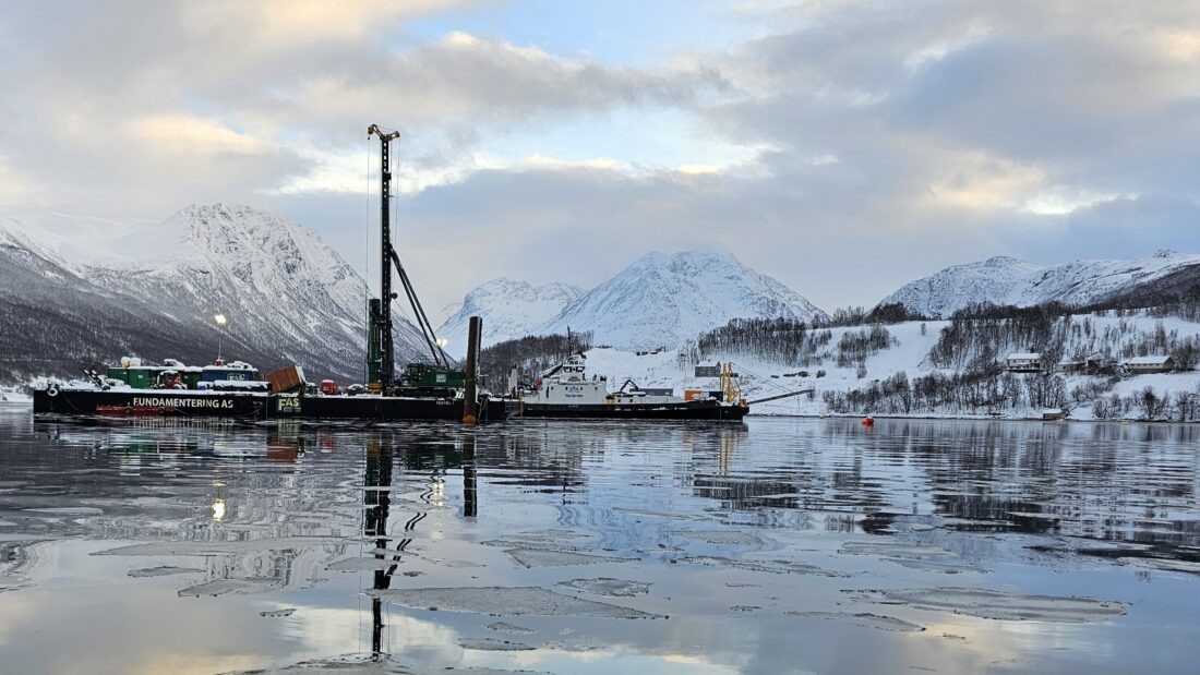 Arbeidet med å banke ned stålpelene som skal bære Ramfjordbroa er ferdig. Fra åsen midt i bildet, skal broa gå ned til sjøfyllinga på andre siden av fjorden. (Foto: Elisabeth Gundersen/Statens vegvesen)