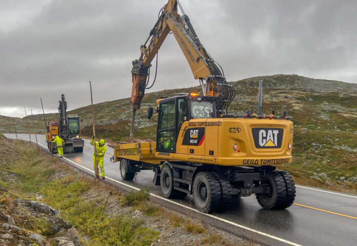 Rv. 7 over Hardangervidda inngår i en stor veidriftskontrakt Presis Vegdrift har i Vestland. Før vinteren setter inn må brøytestikkene på plass. (Foto: Njål Hagen)|Tore Skogheim fra Geilo Tomteservice pigger hull til de fem-seks meter lange trestammene som brukes som brøytestikker over Hardangervidda. Olav Johan Dale har jobben med å løfte brøytestikkene ut av hengeren og plassere dem i hullet. (Foto: Njål Hagen)|Arbeidslaget jobber raskt og det går ikke lang tid mellom hver gang skilter og lysregulering må flyttes på. (Foto: Njål Hagen)|Arbeidslaget består av fem menn som har hver sin oppgave – pigge