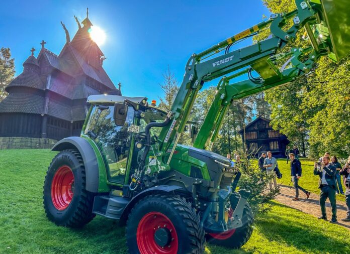Landbruks- og anleggsjournalister fra en lang rekke land hadde funnet veien til lanseringen under vakkert høstvær på Bygdøy i Oslo. (Foto: Runar F. Daler)|Den tyske traktorprodusenten Fendt valgte å legge lanseringen av sin splitter nye elektriske traktor til Norsk Folkemuseum på Bygdøy. Her skinner den om kapp med Gol stavkirke. (Foto: Runar F. Daler)|En god gammeldags avduking av ble gjennomført. Det manglet bare trommevirvler. (Foto: Runar F. Daler)|Vice president i Fendt marketing