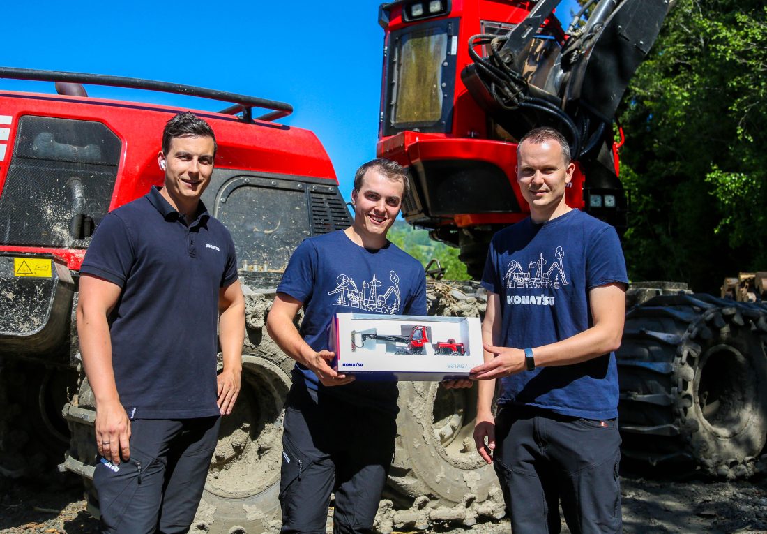 Tord Murbreck (til venstre) og Thomas Jørgensen-Karlsen (til høyre) fra Komatsu Forest Norge overrekker Haakon en Komatsu hogstmaskin i miniatyr; den samme hogstmaskinen han kjører til daglig. (Foto: Runar F. Daler)