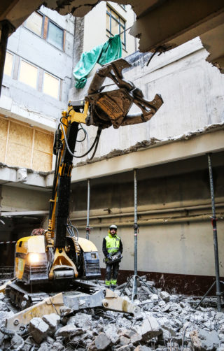 Trygt plassert noen meter unna, står maskinfører Cosmin-Ionut Ioana og styrer rivemaskinen. (Foto: Runar F. Daler).