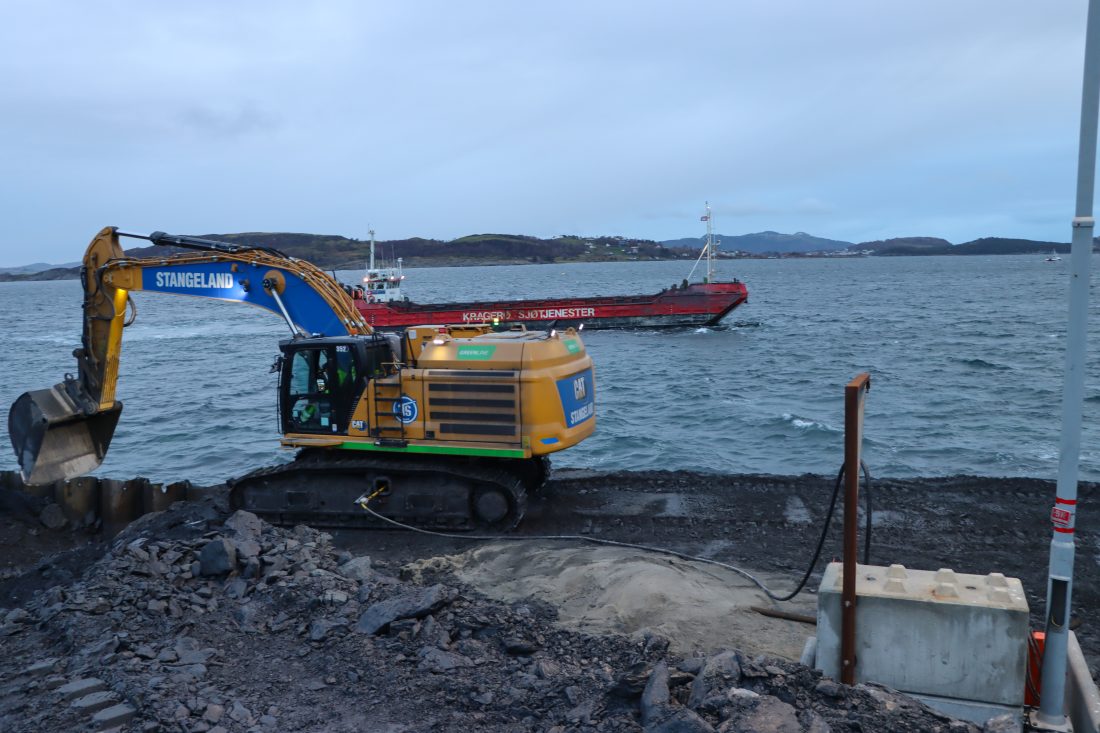 Tunnelmassene skal brukes til å bygge ut næringsområdet i Mekjarvik og lastes over i lekter som tømmer massene i sjøen. Cat 352-graveren er bygget om av Agder Gruppens avdeling i Flekkefjord, Agder Tunnelservice, til diesel/elektrisk hybridmaskin. (Foto: Njål Hagen)