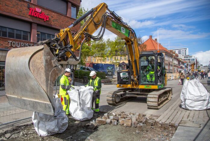 Eksisterende asfalt og gatestein fjernes for å kunne komme til VA-infrastrukturen i grunnen. (Foto: Runar F. Daler)|Store deler av Tromsøs travle hovedgate var gravd opp da Anleggsmaskinen var på besøk i juni. (Foto: Runar F. Daler)|Prosjektet er en del av Tromsø kommunes overordnede plan for overvannshåndtering. (Foto: Runar F. Daler)|Fra venstre: Byggeleder Hans Arne Henriksen fra HRP