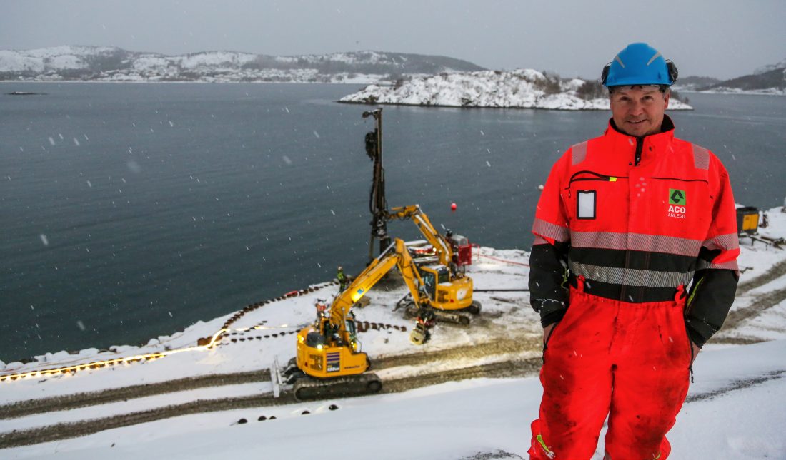 Det er ikke så lett å se med all snøen på bildet, men det er om lag 10 meters høydeforskjell fra øvre del av tomta, der prosjektleder Asle Drabløs i Aco Anlegg står, og ned til sjøen, der maskinene befinner seg. (Foto: Runar F. Daler)