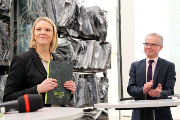 Landbruks- og matminister Sylvi Listhaug har akkurat mottatt Skog22-rapporten. Bak står en applauderende leder for utvalget