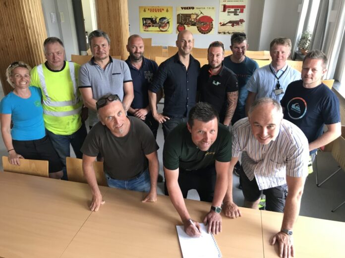 Tore Færevaag fra Os Hageservice AS signerer den nye samfunnskontrakten flankert av Geir Boge fra OKAB og rektor Magnus Vaktskjold fra Stend vgs. Bak ser vi de øvrige anleggsgartnermesterne som var til stede