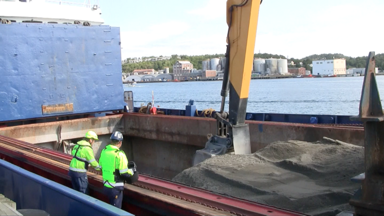 Ronny Sørås fra NCC og Roald Fure fra Skanska inspiserer sanden som skal dekke fjordbunnen. (Foto: Robin Stenersen/NCC).