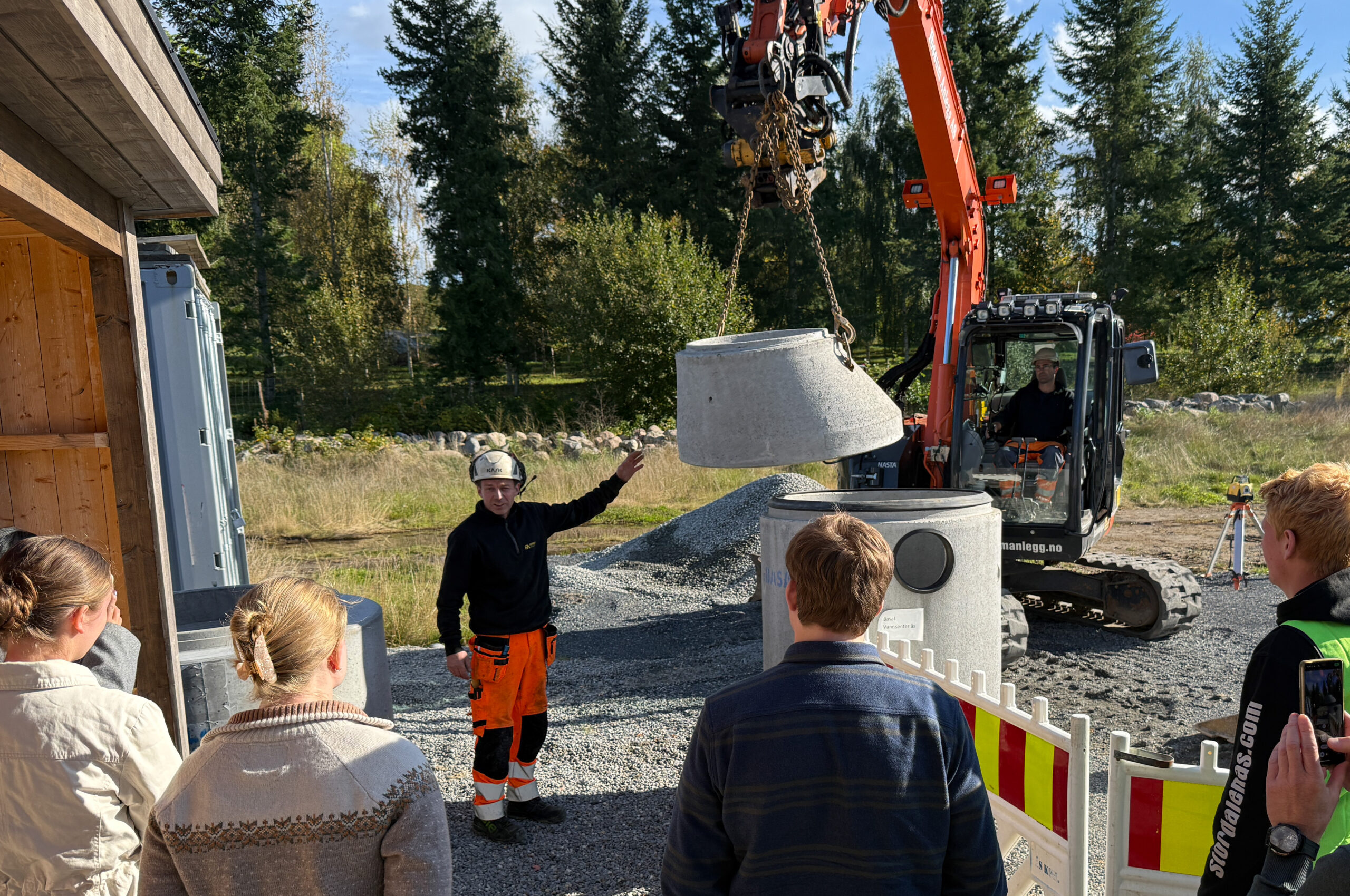 Per-Ivar Nygård hos Fossum Anlegg AS viste og forklarte hvordan man skal legge rør og sette ned kummer, mens maskinfører Tomas Syr utførte jobben. (Foto: Njål Hagen)