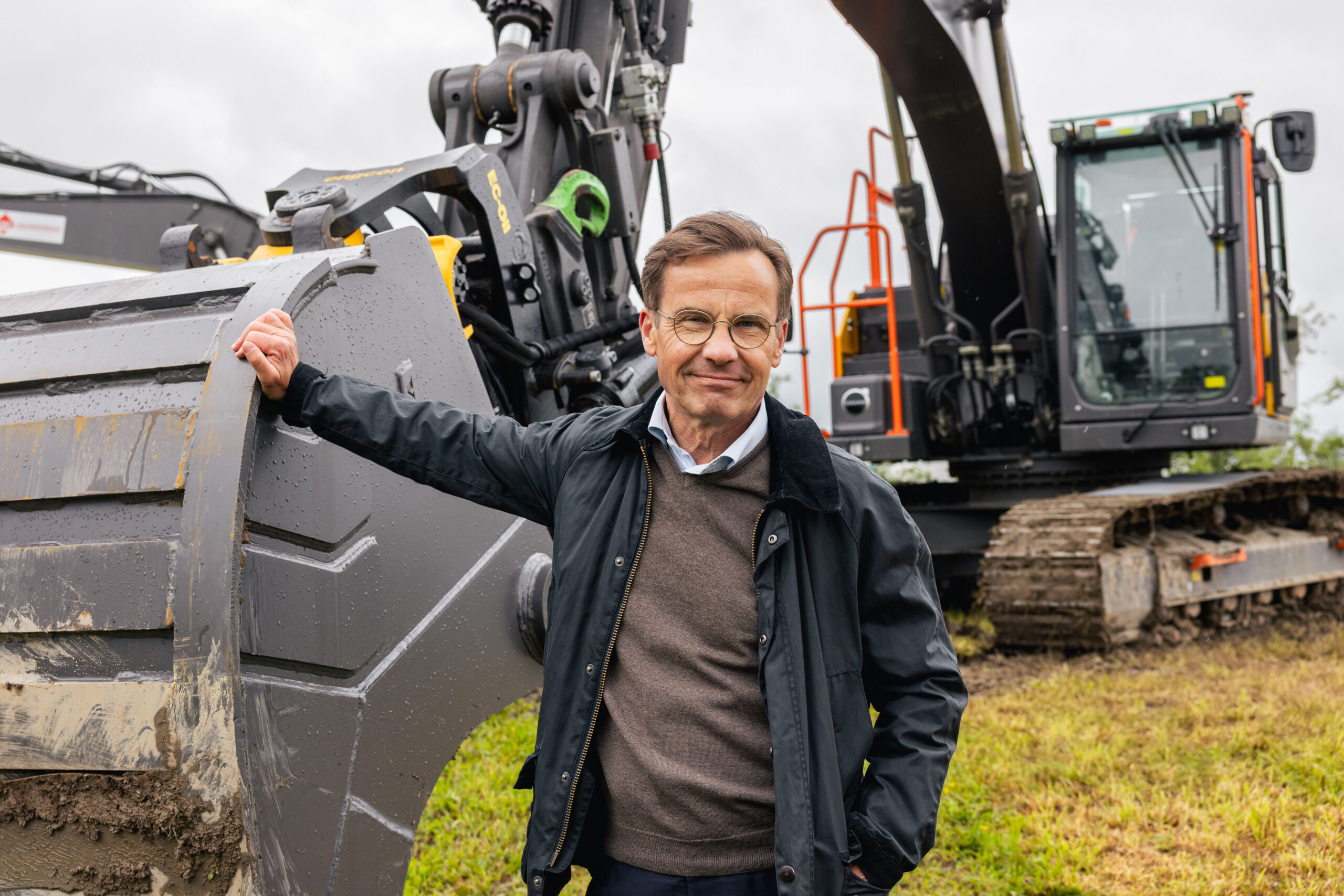 Sveriges statsminister Ulf Kristersson foran den elektriske beltegraveren Volvo EC230 Electric, som er blant gravemaskinene som skal produseres ved den nye fabrikken i Eskilstuna. (Foto: Volvo CE)