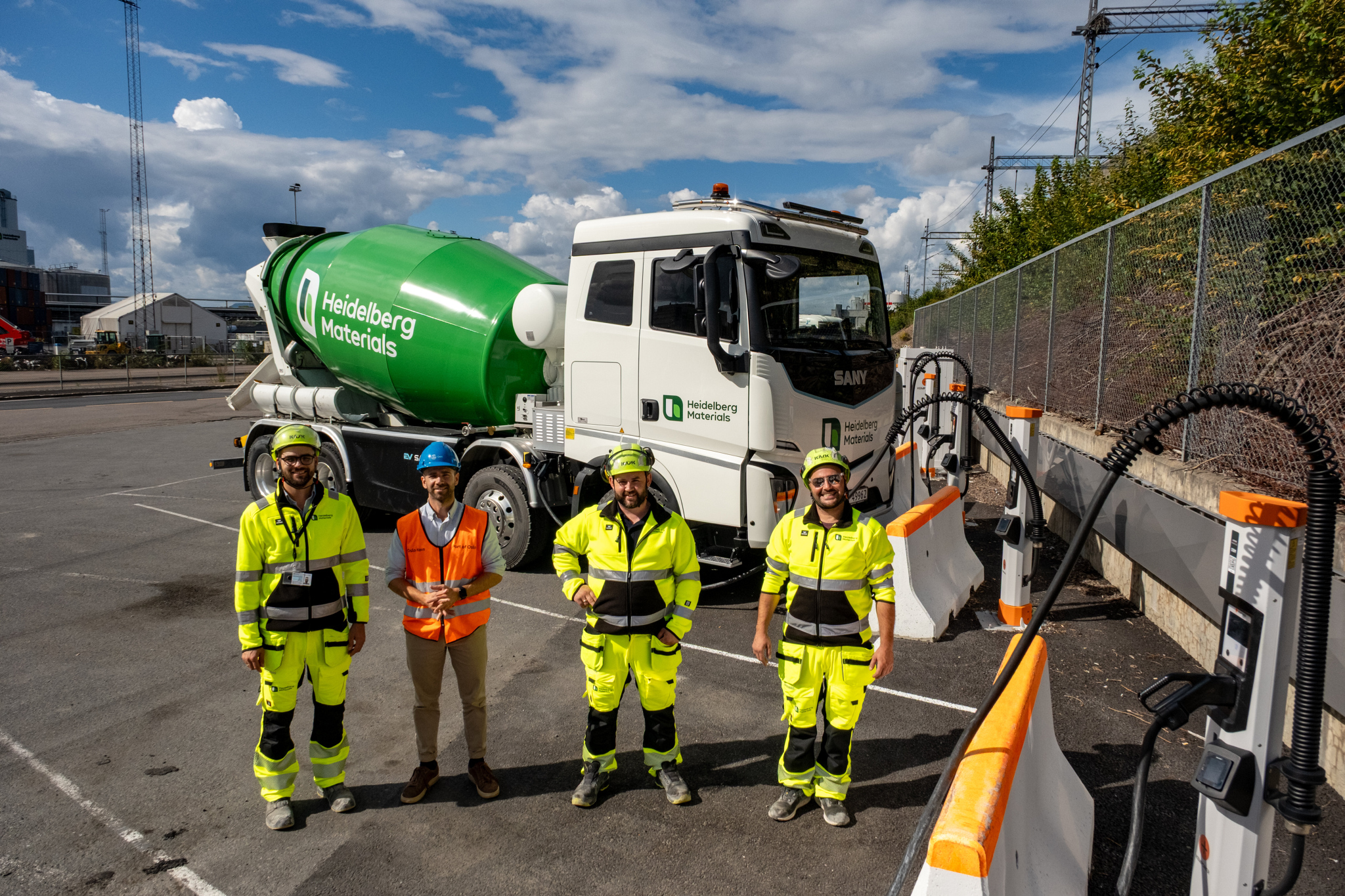 LADEINFRASTRUKTUR: I nærheten av Heidelberg Materials betongfabrikk på Sjursøya kan kjøretøyene benytte felles ladeanlegg for tungtransporten, bygget av Oslo Havn. Fra venstre: Peter Holiman Kermit, Jens Eirik Hagen John Edvin Tornes og Georgi Stoyanovq. (Foto: Hans Kristian Riise/Oslo Havn)